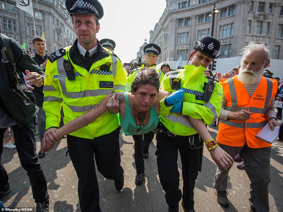 Police remove a woman from the Extinction Rebellion climate protests in Oxford Circus this afternoon